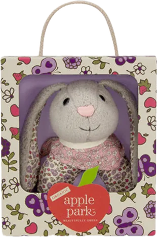 A grey knit bunny rattle in a floral window box with a rope handle and a red apple park apple.