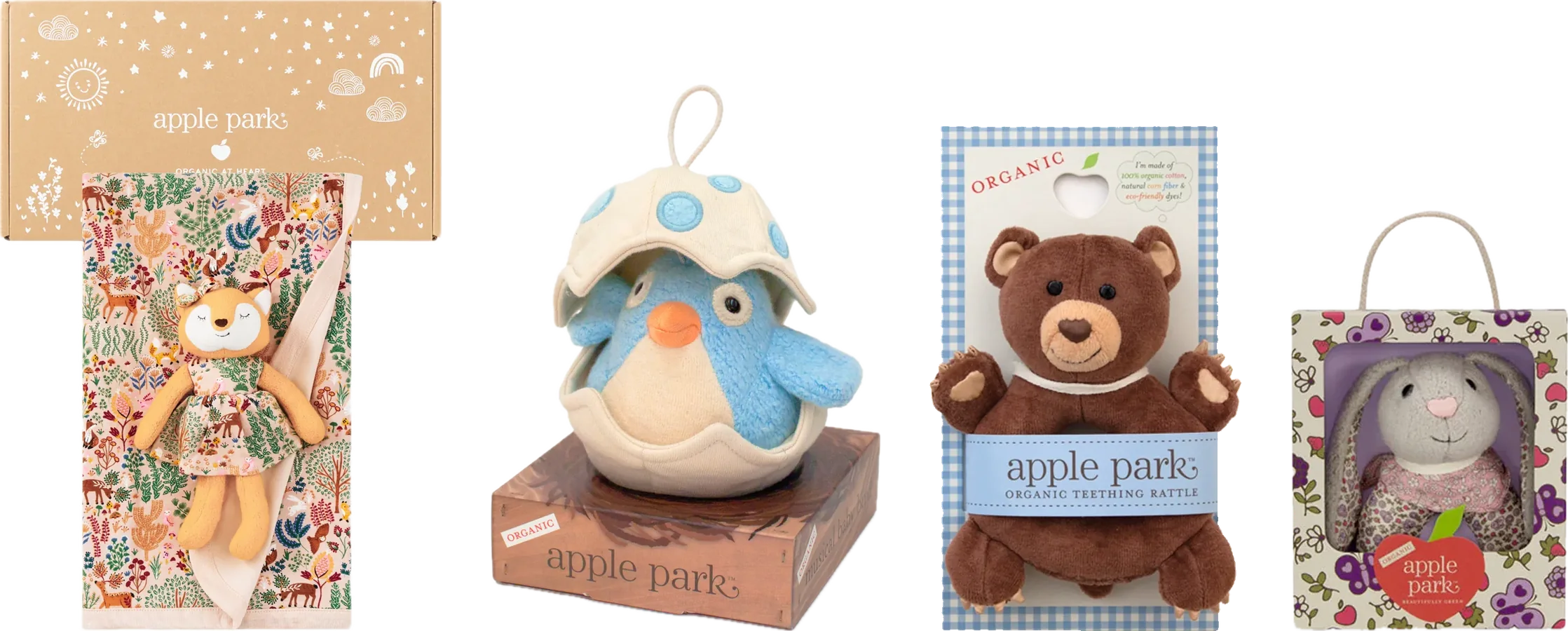 Four Apple Park packages in a row: a kraft gift box with a blanket and fox plush, a bird toy on a printed nest box, a bear rattle on a gingham backcard, and a bunny in a floral window box.