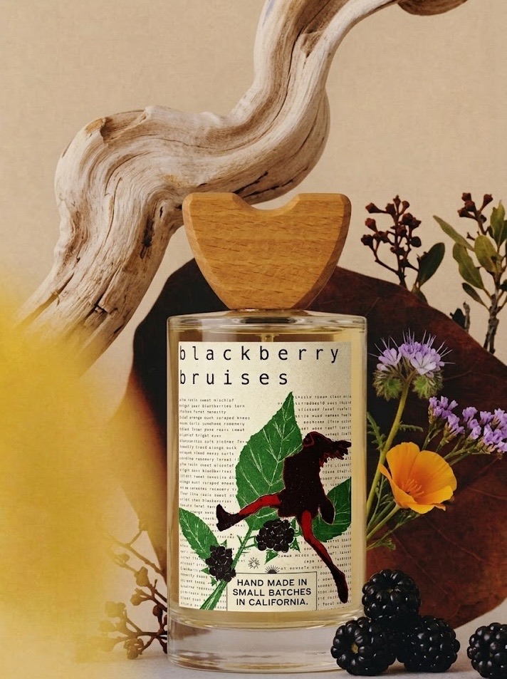 Blackberry Bruises fragrance bottle with a linocut-style label of a feral figure running through blackberry brambles.