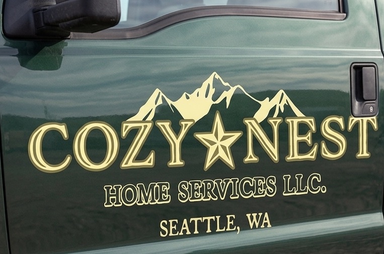 The Cozy Nest logo as a decal on a dark green truck door: mountains, a star, and Home Services LLC, Seattle, WA.
