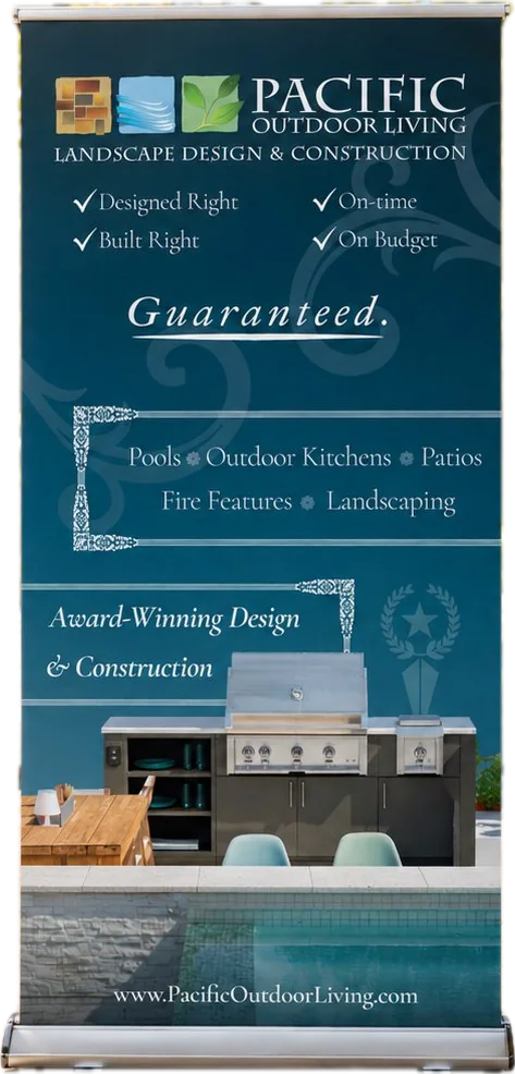 A Pacific Outdoor Living pull-up banner listing pools, outdoor kitchens, patios, fire features and landscaping, under the words Guaranteed and Award-Winning Design and Construction.