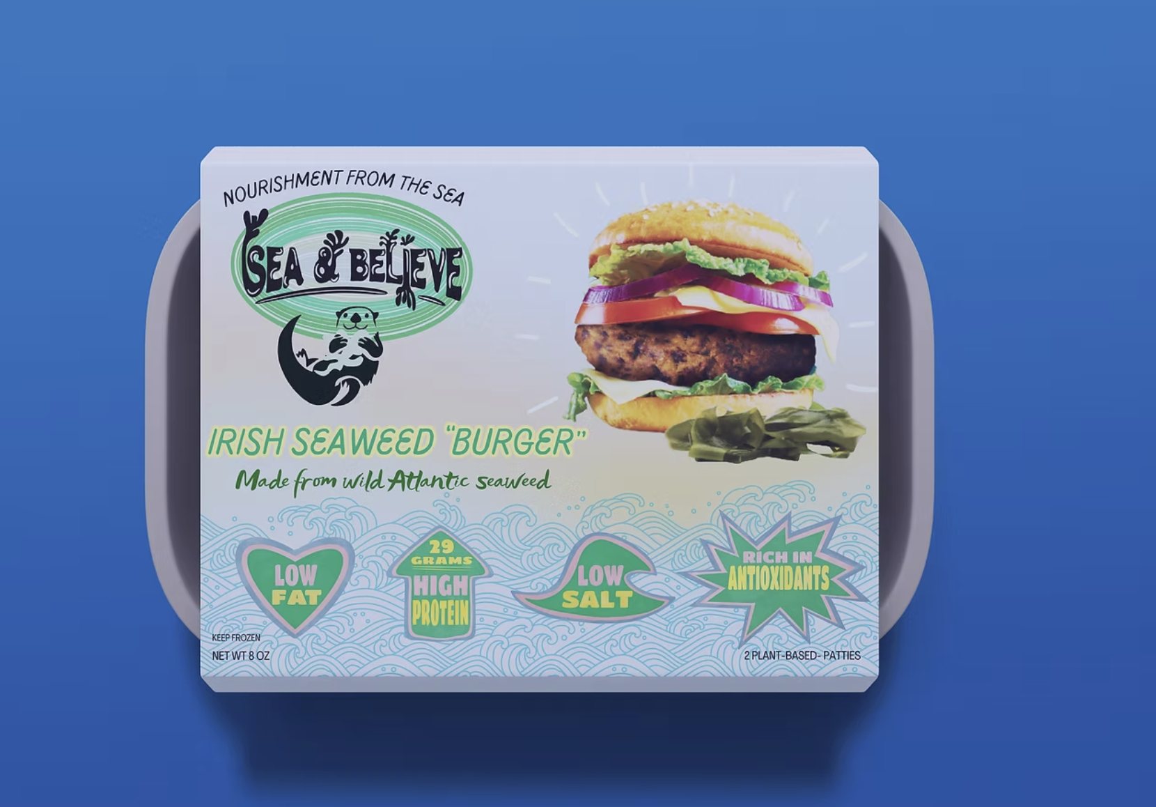 Sea & Believe Irish seaweed burger in a clear-lidded tray on a blue ground, showing the burger built into a bun with lettuce and tomato.